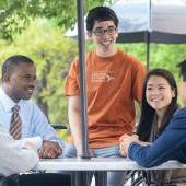 A group of McCombs students chat with each other outside of the school.